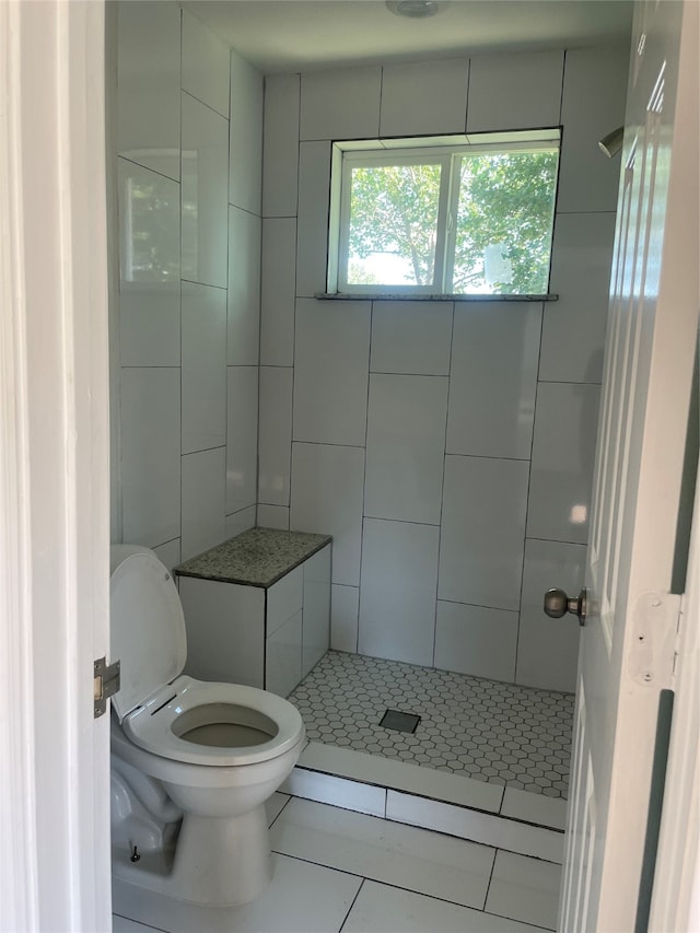 bathroom with tile patterned flooring, toilet, and a tile shower