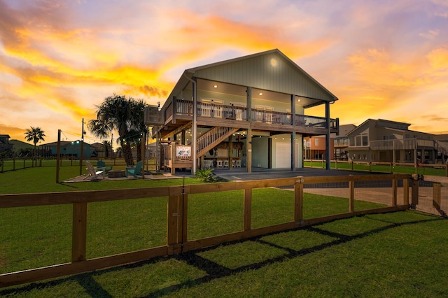 back house at dusk with a lawn, a wooden deck, and a garage