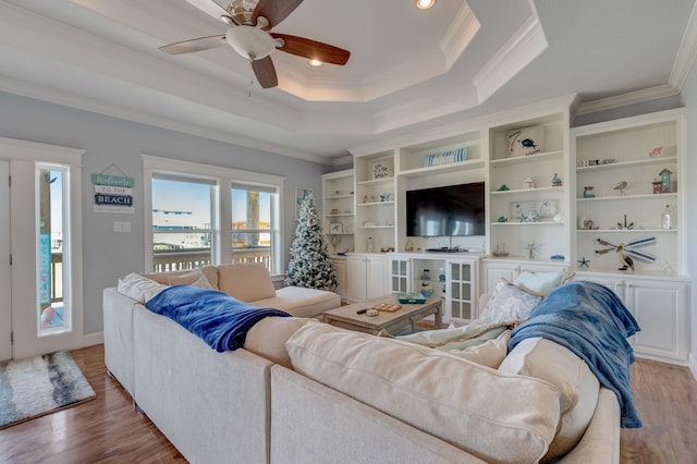 living room with hardwood / wood-style flooring, a raised ceiling, ceiling fan, and crown molding