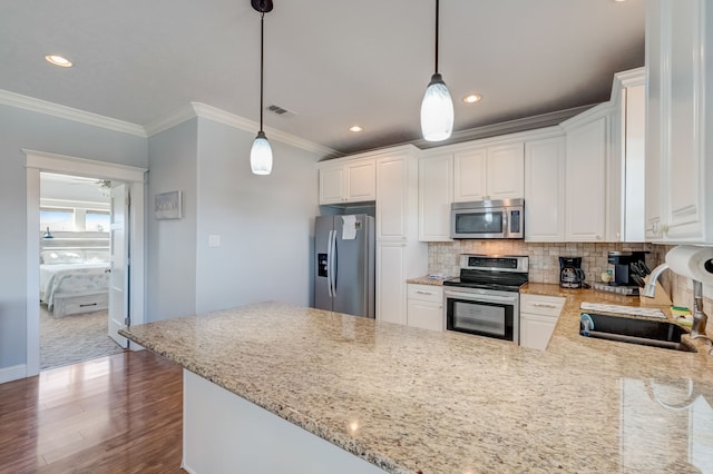 kitchen with hanging light fixtures, white cabinetry, sink, and stainless steel appliances