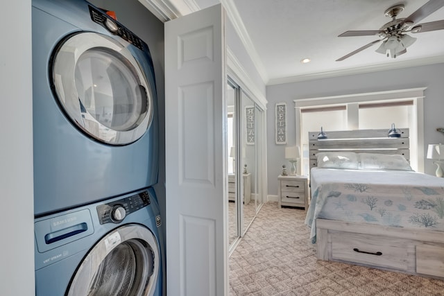 clothes washing area featuring light colored carpet, stacked washer / dryer, ornamental molding, and ceiling fan