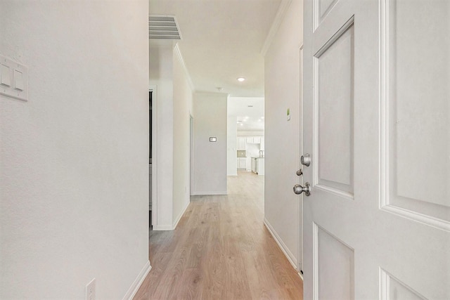 corridor with crown molding and light hardwood / wood-style floors