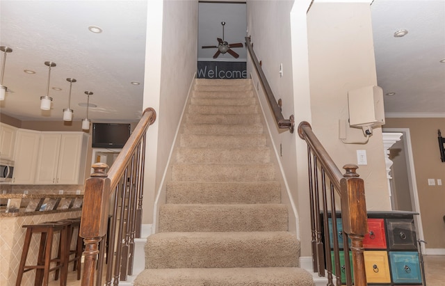 stairs featuring carpet flooring, crown molding, and ceiling fan