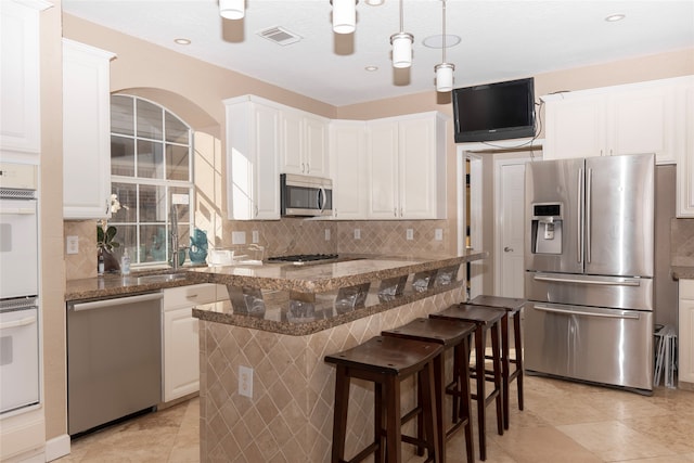 kitchen with white cabinets, dark stone counters, and appliances with stainless steel finishes