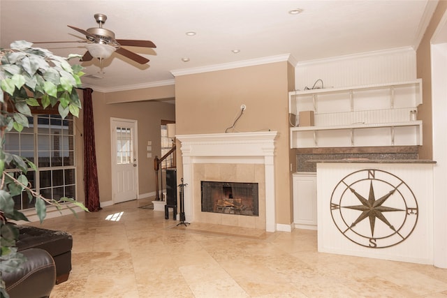 living room featuring a tile fireplace, ceiling fan, and crown molding