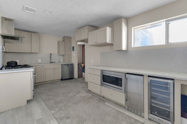 kitchen featuring sink, stainless steel appliances, wine cooler, a textured ceiling, and exhaust hood