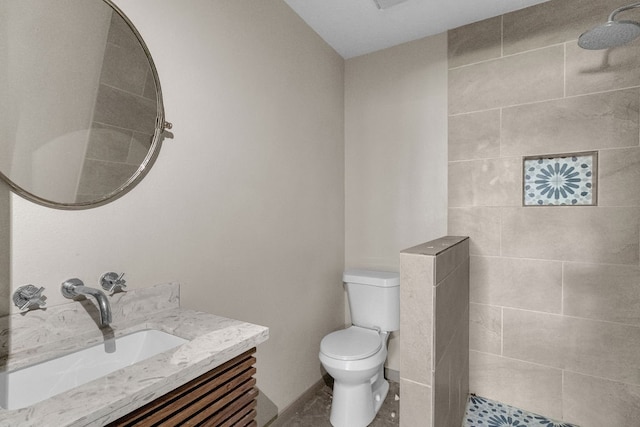 bathroom with toilet, vanity, and tiled shower