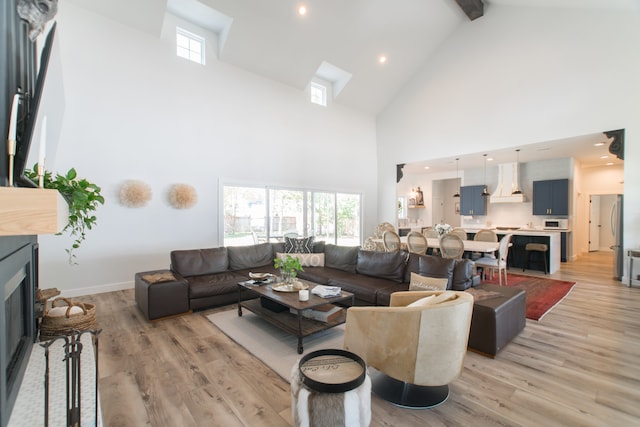 living room with beamed ceiling, high vaulted ceiling, and light hardwood / wood-style flooring