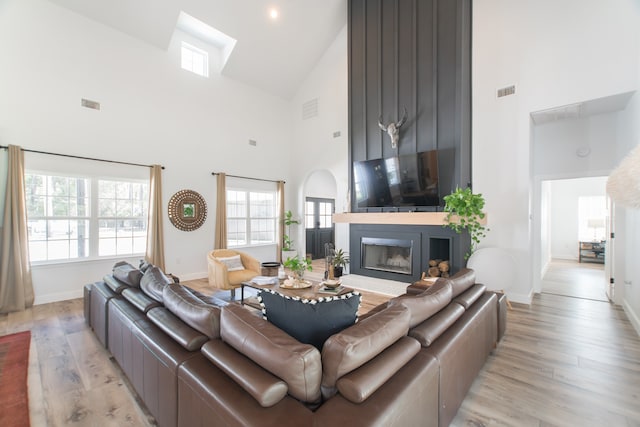 living room featuring high vaulted ceiling and light wood-type flooring