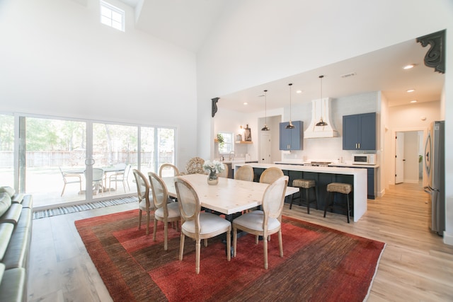 dining space featuring a high ceiling, light hardwood / wood-style flooring, and sink