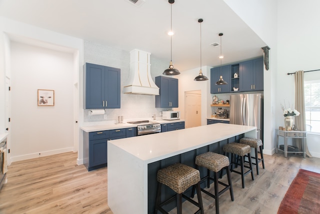 kitchen featuring blue cabinetry, premium range hood, appliances with stainless steel finishes, and light hardwood / wood-style flooring