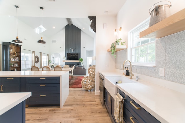 kitchen featuring lofted ceiling with beams, hanging light fixtures, light hardwood / wood-style floors, and sink