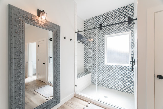 bathroom with hardwood / wood-style floors and an enclosed shower