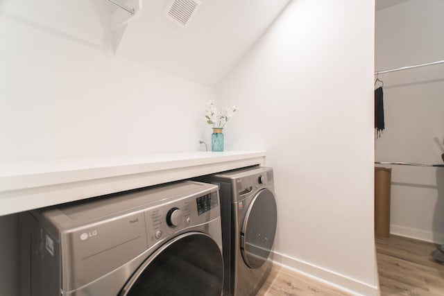 laundry area featuring washer and dryer and light hardwood / wood-style floors