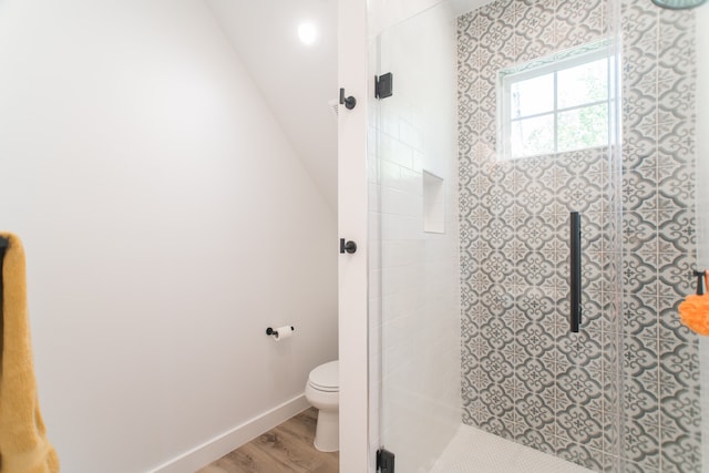 bathroom with wood-type flooring, toilet, and a shower with shower door