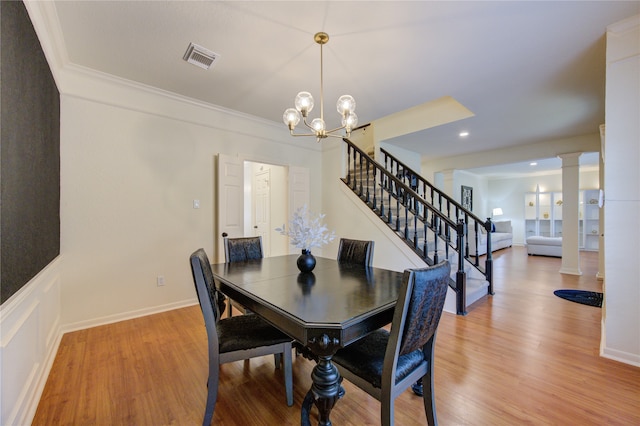 dining space with light hardwood / wood-style floors, an inviting chandelier, crown molding, and decorative columns