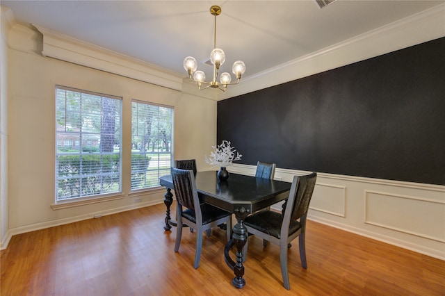 dining room featuring crown molding, hardwood / wood-style floors, a healthy amount of sunlight, and a notable chandelier