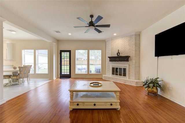 unfurnished living room with a fireplace, light wood-type flooring, and ceiling fan