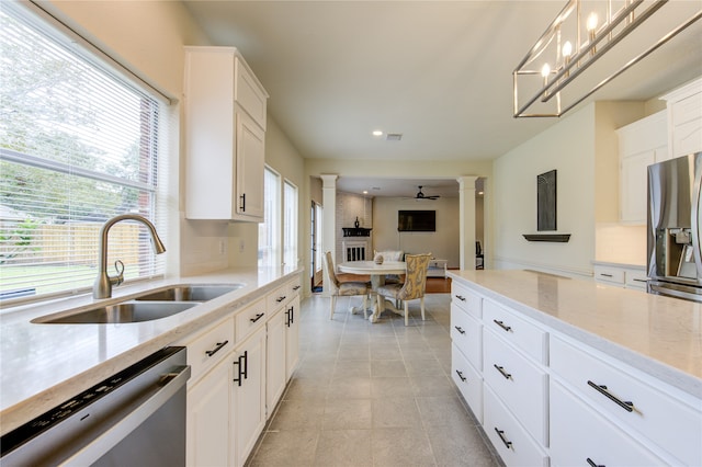 kitchen featuring decorative columns, sink, white cabinets, and appliances with stainless steel finishes