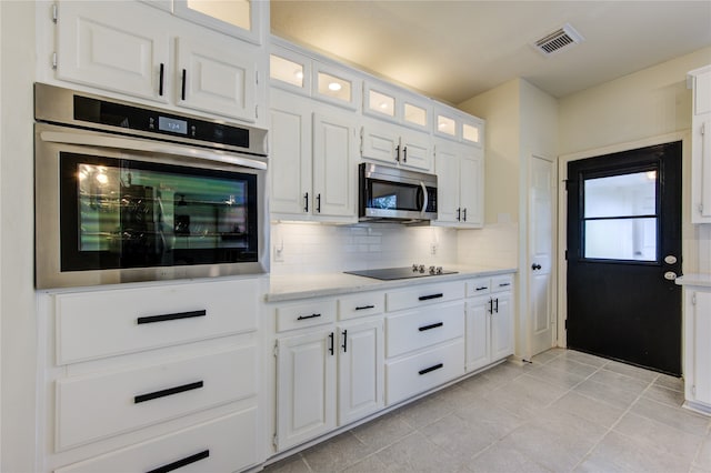 kitchen featuring light tile patterned floors, stainless steel appliances, white cabinetry, and tasteful backsplash