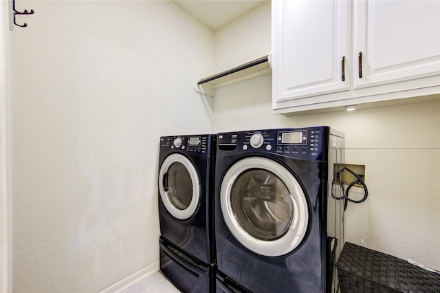 clothes washing area featuring cabinets and washing machine and clothes dryer