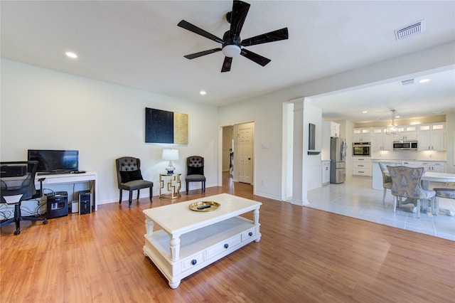 living room featuring ceiling fan, light hardwood / wood-style floors, and ornate columns