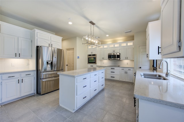 kitchen featuring appliances with stainless steel finishes, sink, pendant lighting, white cabinetry, and a kitchen island