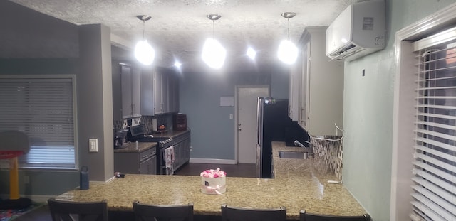 kitchen with decorative light fixtures, stainless steel appliances, sink, kitchen peninsula, and a wall mounted air conditioner