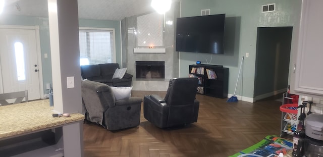 living room featuring a tile fireplace and dark parquet flooring