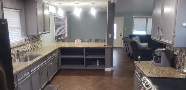 kitchen featuring kitchen peninsula, sink, tasteful backsplash, gray cabinetry, and dark parquet flooring