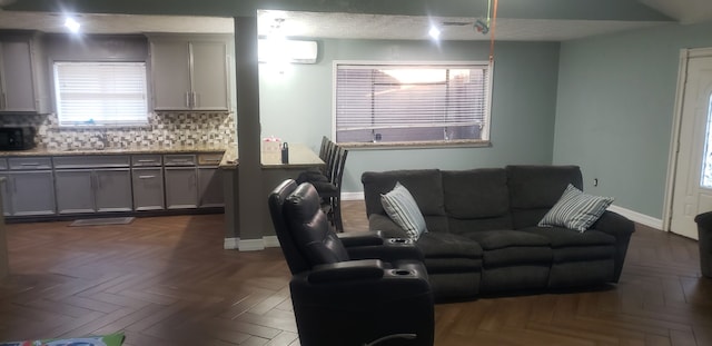 living room with an AC wall unit, sink, and dark parquet flooring