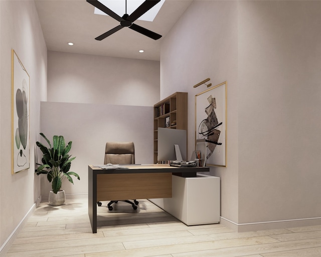 home office with a towering ceiling, light wood-type flooring, and ceiling fan