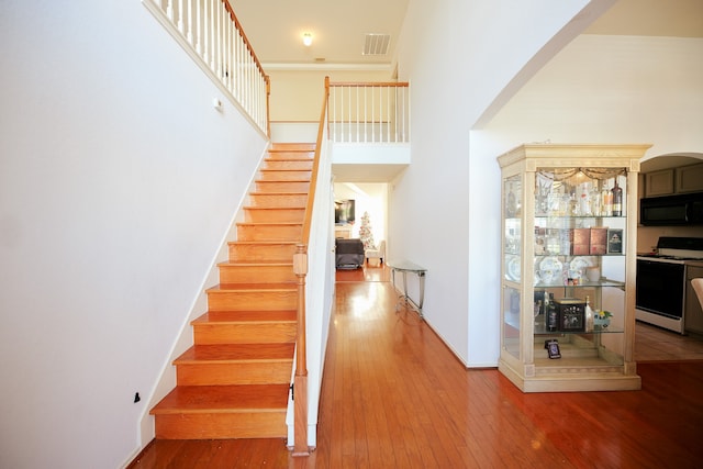 stairs featuring hardwood / wood-style floors, crown molding, and a high ceiling