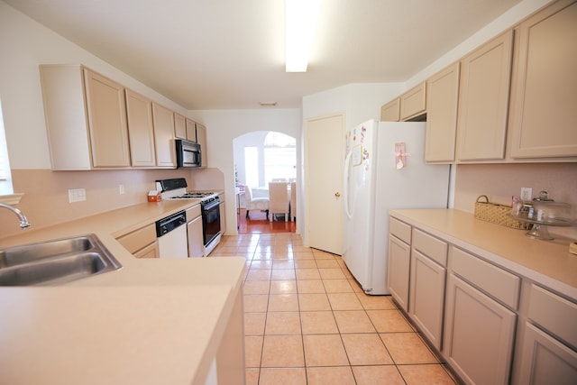 kitchen featuring light tile patterned flooring, cream cabinetry, white appliances, and sink