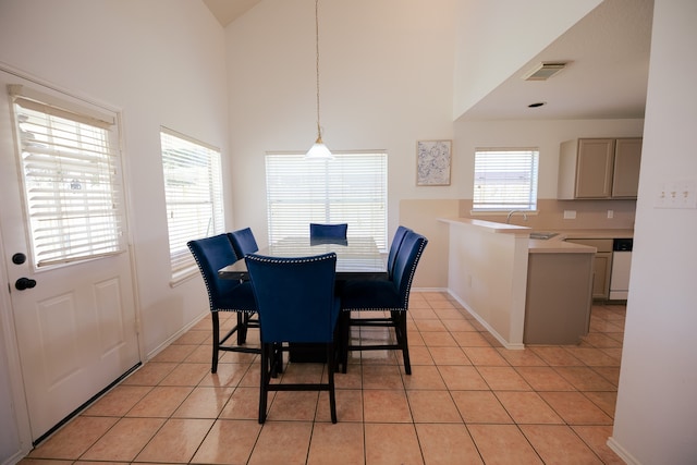 dining room with a healthy amount of sunlight, a towering ceiling, sink, and light tile patterned floors