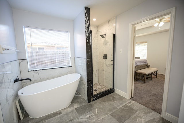 bathroom with ceiling fan, plus walk in shower, and tile walls