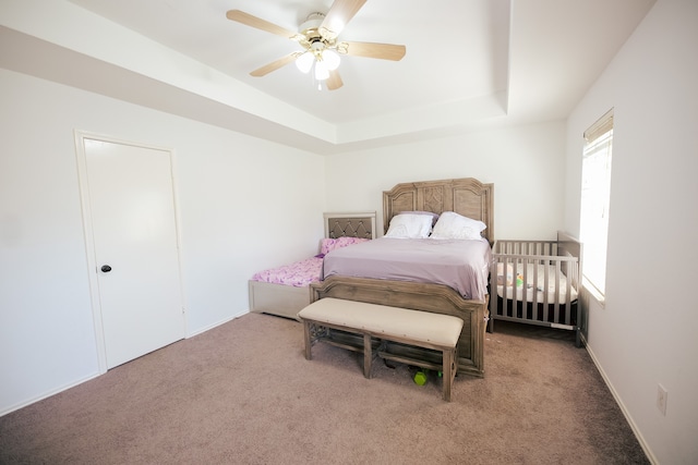 bedroom with ceiling fan, a raised ceiling, and carpet floors