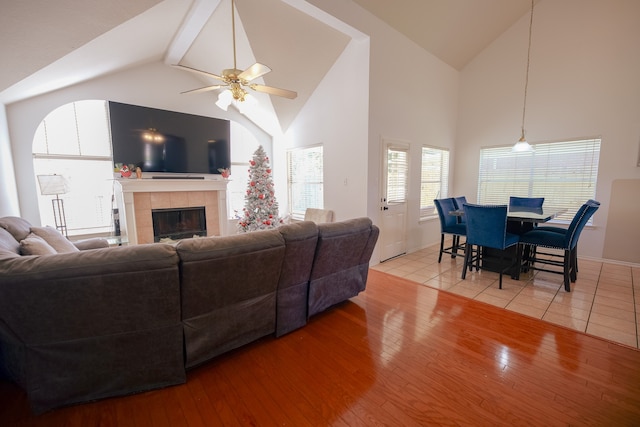 living room with ceiling fan, a fireplace, high vaulted ceiling, and light hardwood / wood-style flooring