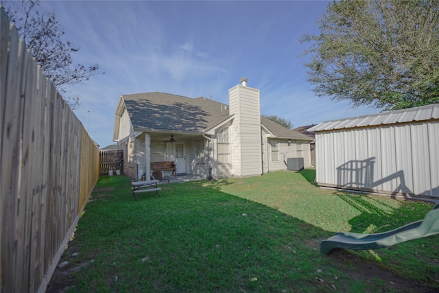 back of property featuring a yard, a shed, ceiling fan, and central air condition unit