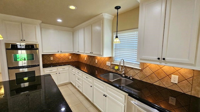 kitchen with sink, white cabinets, stainless steel appliances, and decorative light fixtures