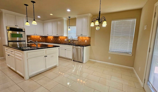 kitchen with sink, stainless steel appliances, backsplash, decorative light fixtures, and a kitchen island with sink