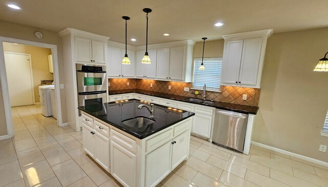 kitchen featuring a center island with sink, hanging light fixtures, sink, and appliances with stainless steel finishes