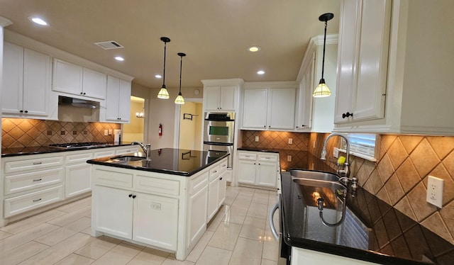 kitchen featuring white cabinetry, an island with sink, and hanging light fixtures