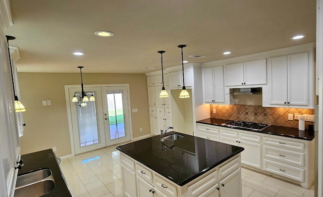 kitchen with white cabinets, an inviting chandelier, a kitchen island with sink, and sink