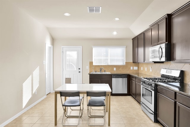 kitchen featuring a kitchen bar, decorative backsplash, stainless steel appliances, a center island, and lofted ceiling