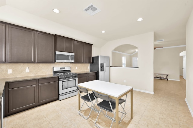 kitchen featuring dark brown cabinets, light stone counters, stainless steel appliances, and tasteful backsplash