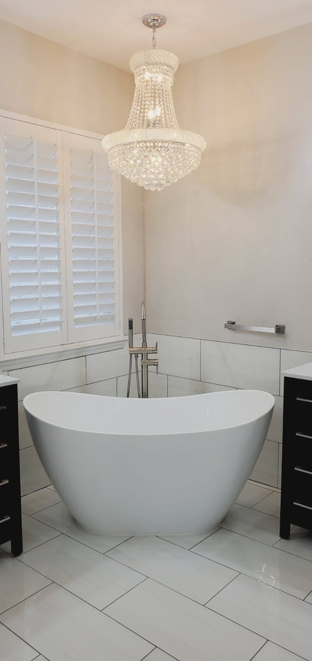 bathroom featuring vanity, a bathtub, tile walls, and an inviting chandelier