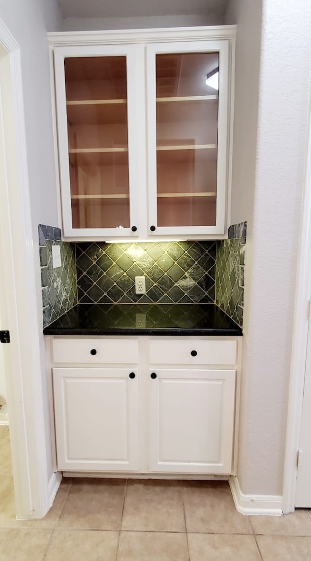 bar with tasteful backsplash, white cabinets, and light tile patterned floors