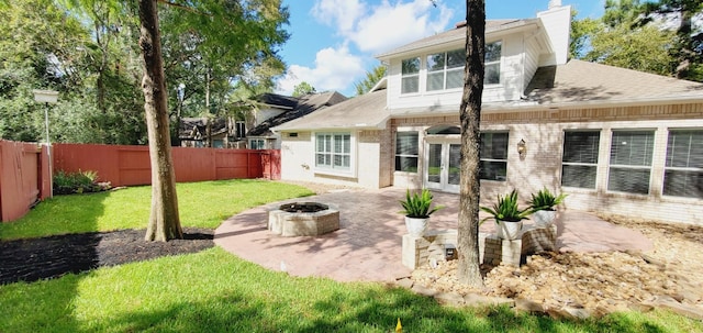 back of property with a lawn, an outdoor fire pit, a patio, and french doors