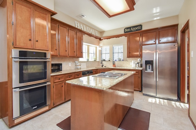 kitchen with tasteful backsplash, stainless steel appliances, sink, light tile patterned floors, and a center island